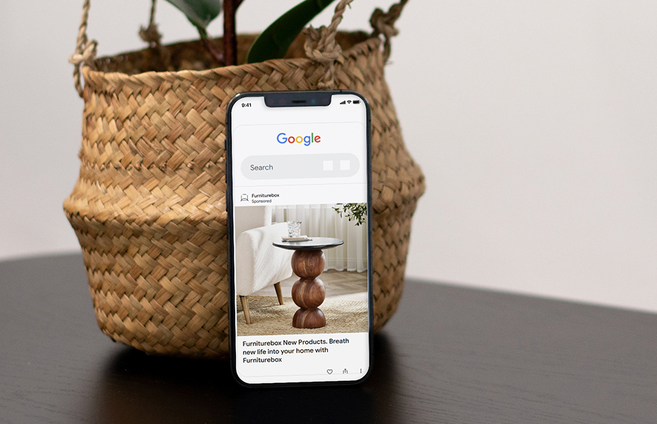 Mobile mockup of a Furniturebox Google Ad leaning against a plant pot
